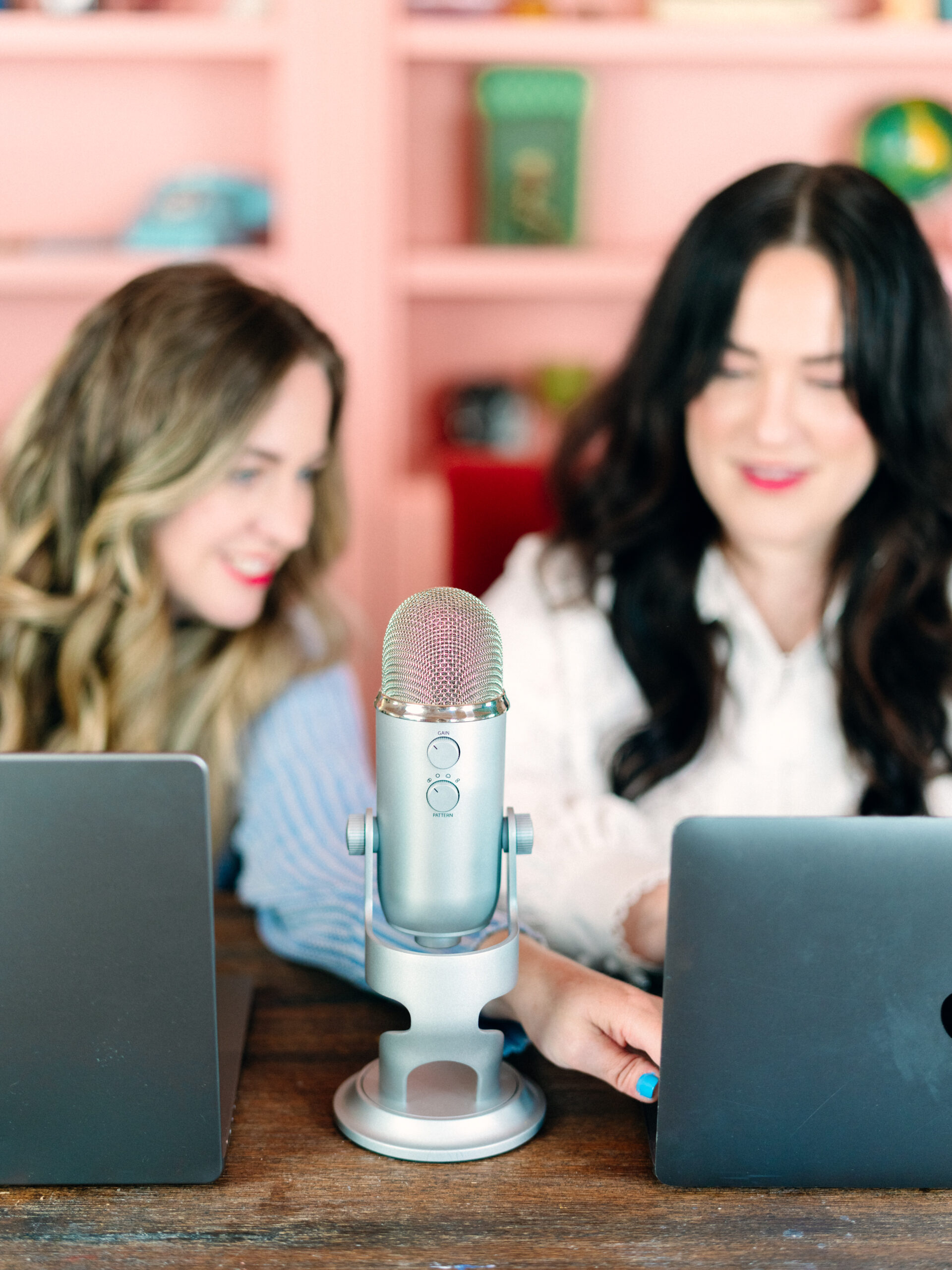 Charla Storey & Jennefer Wilson looking at computer while recording a podcast episode